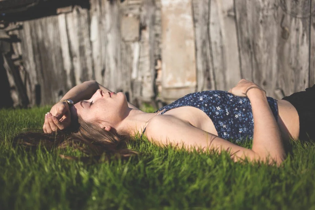 Jeune femme zen dans l'herbe après un soin énergétique complet