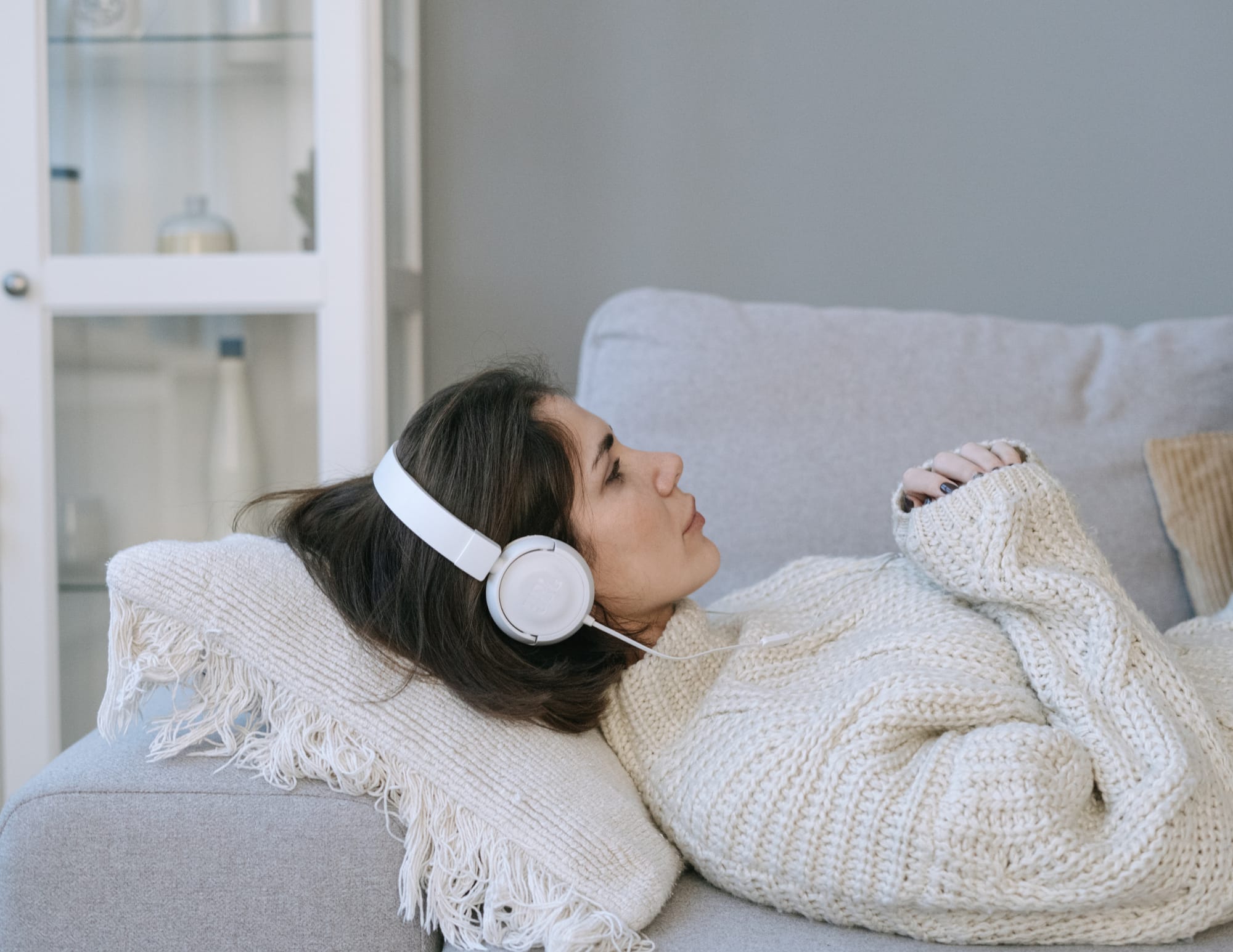 Une femme chez elle avec un plaid, les yeux fermés, recevant un soin de Reiki à distance
